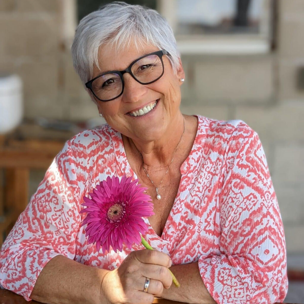 Portrait von Frau Fecht, die eine Blume in der Hand hält.